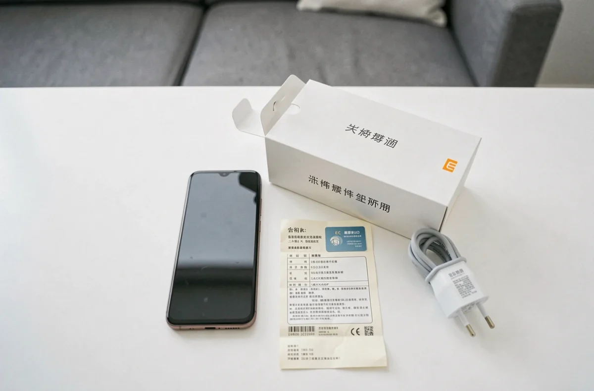 Smartphone Xiaomi importé posé avec boîte chinoise, carte de garantie et adaptateur secteur EU